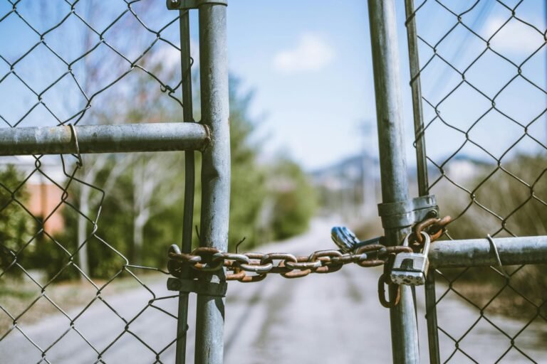 Locked metal chain and padlock securing a gate, representing barriers to entry for new market entrants