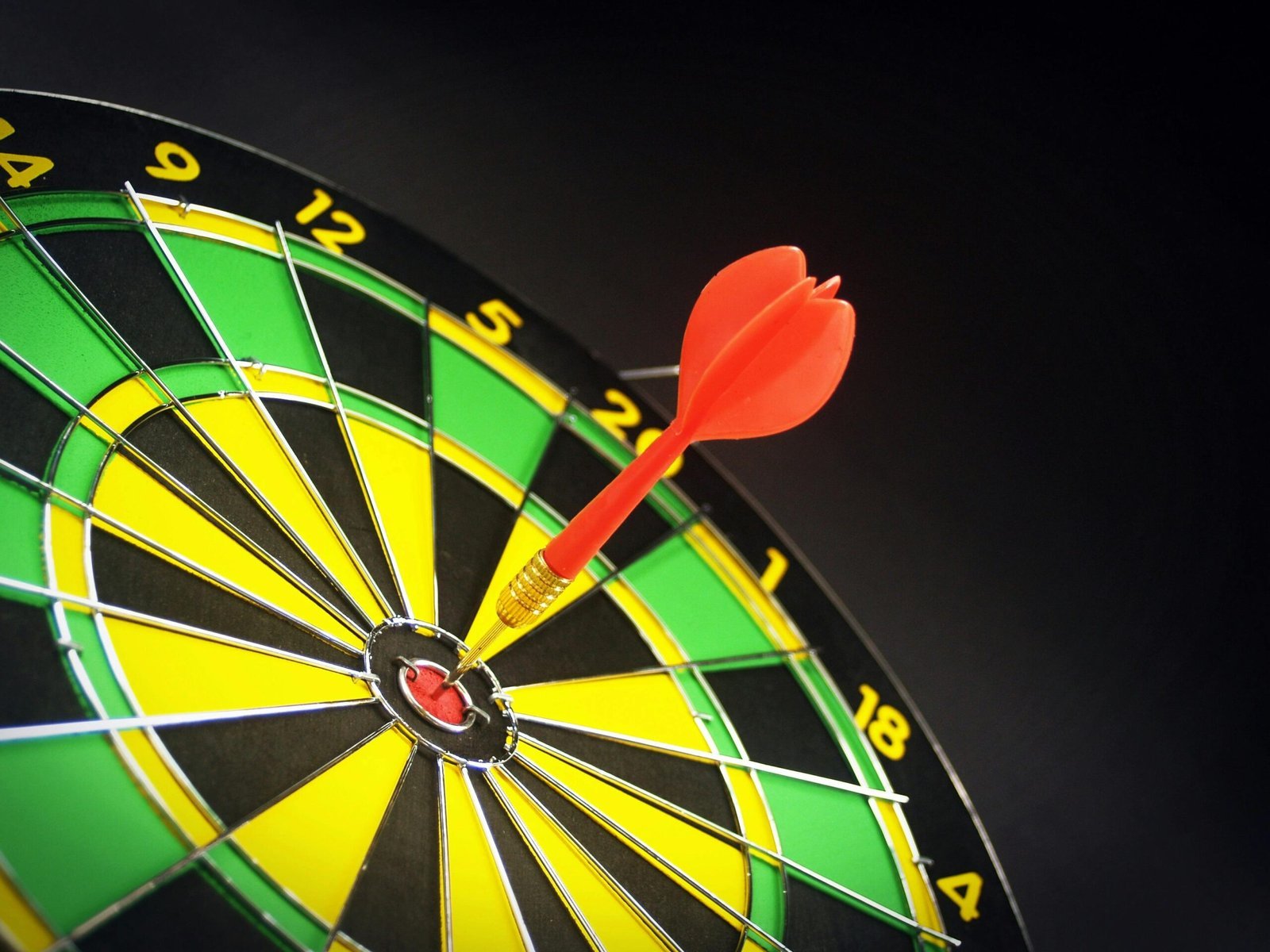 Close-up of a dart hitting the bullseye on a dartboard, symbolizing segmentation, targeting and positioning in marketing strategy