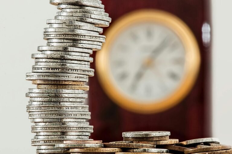 Stack of silver coins in front of a blurred gold-rimmed clock symbolizing corporate finance and time value of money