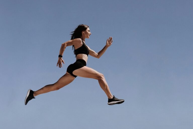 Female athlete leaping in mid-air against blue sky, symbolizing speed, efficiency, and performance in supply chain run time and capacity