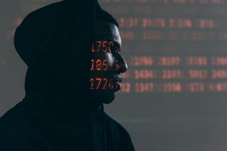 A side profile of a person in a dark hoodie with red digital numbers and data patterns projected onto their face and the background, symbolizing the matrix representation of data.
